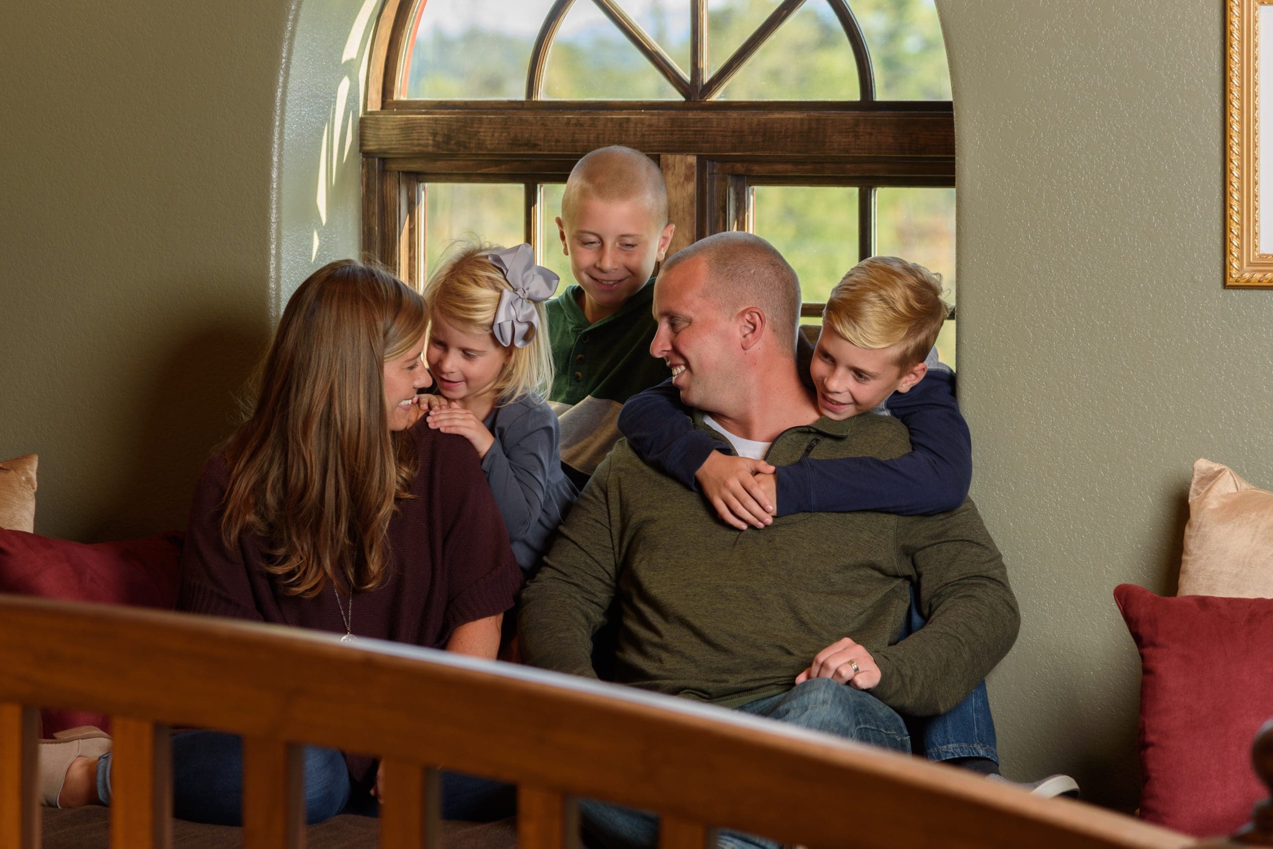 A family of five sitting together by a window, smiling and hugging each other warmly, reflecting the joy of intentional gatherings with friends and family.